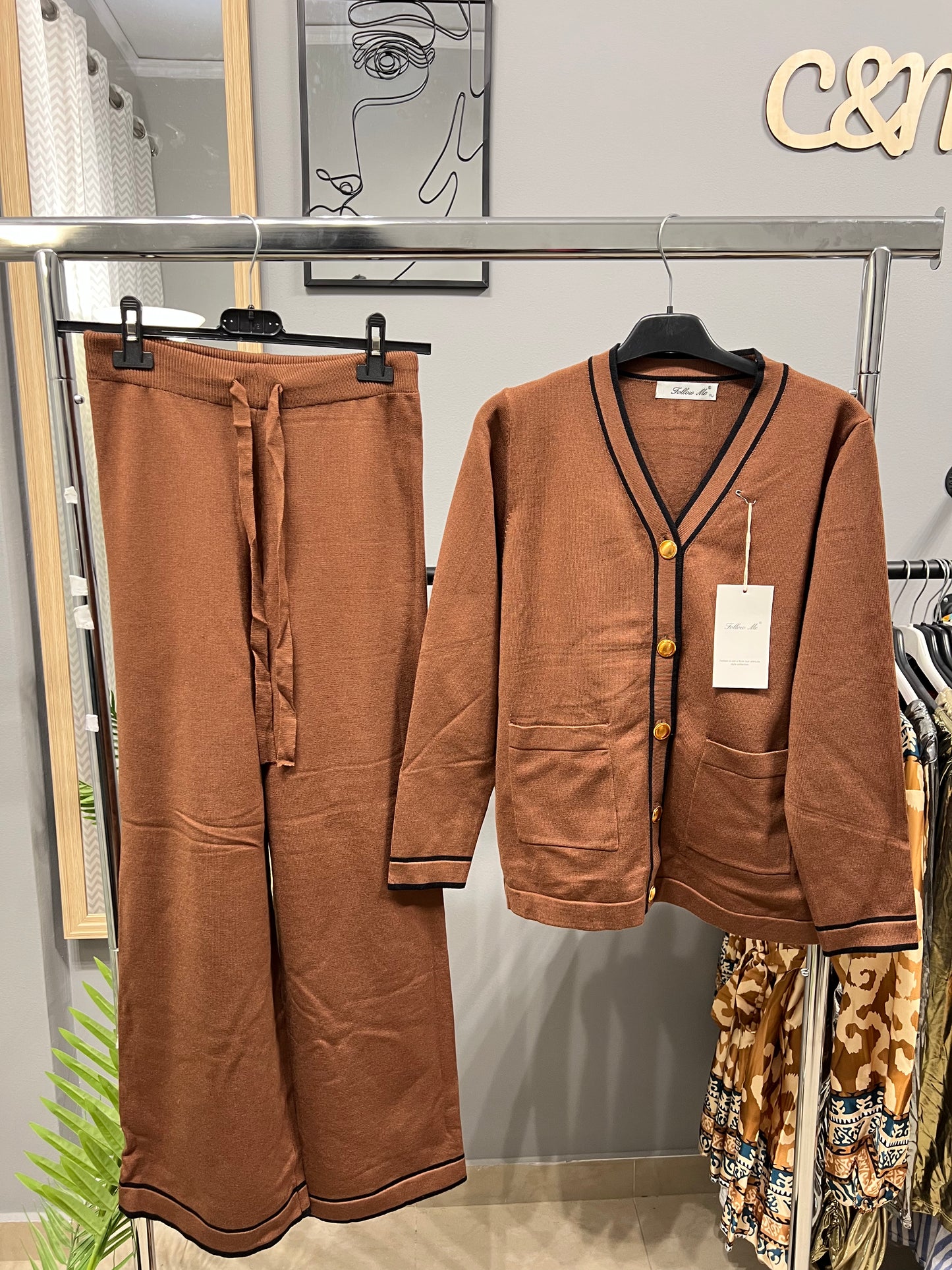 Καφέ πλεκτό σετ με ζακέτα V-neck και φαρδύ παντελόνι κρεμασμένο σε κρεμάστρα. Vintage στυλ με σκούρες ρίγες στα τελειώματα, χρυσά κουμπιά και δύο τσέπες. One size fits XS-L"