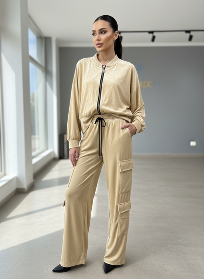 Μοντέλο φορώντας βελούδινο κρεμ bomber jacket και cargo παντελόνι σε μοντέρνο εσωτερικό χώρο